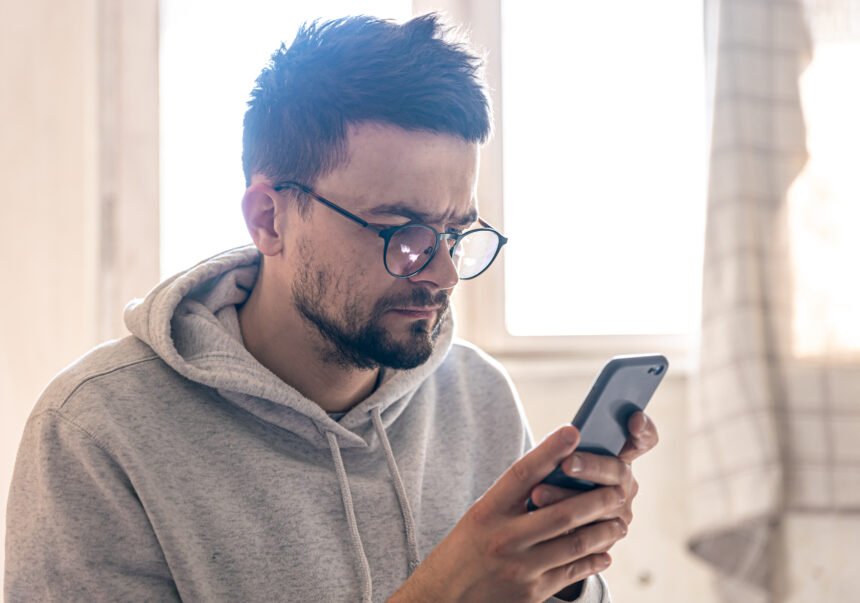 A man with glasses uses a smartphone, copy space. Com o fim das bets, especialista explica como reorganizar as finanças